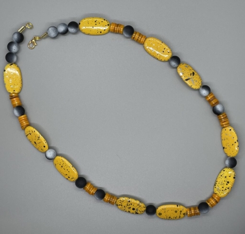Unisex Neckwear- Black and White Round Rubber Coated Glass Beads. Yellow Speckled Metal Oval Beads. Orange Heishi Shell Beads. Approx. length: 22 inches. Pronounced: AH-DAH-EH. Origin: Africa. Meaning: Morning Sun