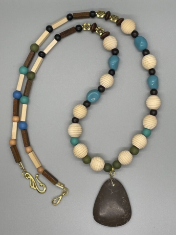 Unisex Neckwear- 4 Sided Beige and Brown Wood Beads. Blue, Green and Turquoise Round Glass Beads. Small Round Beige and Black Wood Beads. Gold Metal Diamond Etched Design Accents. Brown Puffed Rondelle Beads. Natural Wood Beehive Beads. Polished Turquoise Acrylic Beads. 2 1/2 inch Bone Pendant. Approx. length: 31 inches. Pronounced: B-OH-MAH-NEE. Origin: Africa. Meaning: Great Warrior