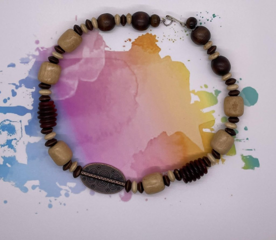 Unisex Choker- Round Polished Natural Wood Beads. Block Natural Wood Beads. Dark Red Polished Ribbed Wood Barrel Beads. Brown and Beige Puffed Rondelle Beads. Engraved Copper Pendant. Approx. length: 18 inches. Pronounced: EH-mem Origin: Africa Meaning: Person of Peace