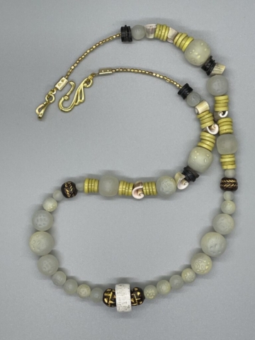 Unisex Neckwear- Brass Rounded Rectangle Beads. Coconut Disc Beads. Green Tinted Small, Medium and Large Round Dimpled Acrylic Beads. Polished Sea Shells Chips. Brown and Gold Clay Beads. Yellow Heishi Shell Discs. Vintage Porcelain Gold Spotted Heishi Beads. Approx. length: 24 inches. Pronounced: JAH-FAH-REE. Origin: Africa. Meaning: Stream