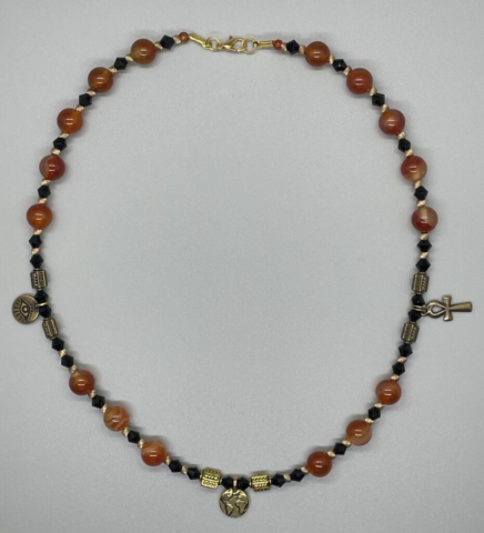 Unisex Neckwear- Small Glass Round Bead Accents. Gold Metal Ribbed Accents. Black Opaque Czech Crystal Bicone Beads. Round Carnelian Beads. Gold Metal and Pewter Etched Accent Beads. Pewter and Gold Metal Eye, Ankh and World Accents. Approx. length: 19 inches. Pronounced: SUH-LASS-SEE. Origin: Igbo. Meaning: One that refers to a Trinity