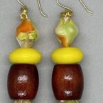 Earrings- Transparent Acrylic Swirl Bead. Vintage Sun Yellow Opaque Pressed Glass Beads. Dark Brown Barrel Wood Beads. Approx. length: 2 1/2 inches. Hand Shaped 14K Gold Filled Earwire. Pronounced: AH-BREE-HET. Origin: Africa. Meaning: Shines with Light