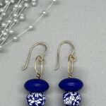 Earrings- Blue Pressed Glass Beads. Blue and White Silicone Round Beads. Orange Acrylic Floral Design Accents. Vintage Fluted Rondell Acrylic Beads. Approx. length: 2 1/4 inches. Hand Shaped .925 Sterling Silver Earwire. Pronounced: AH-LEE-KAH. Origin: Africa. Meaning: Most Beautiful