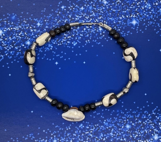 Ankle Bracelet- Polished Brown Wood Beads. Silver Metal Hollow Tube Beads. Swirl Design Batik Bone Beads. Silver Metal Bicone Beads. Cowrie Shell Centerpiece. Approx. length: 10 inches. Pronounced: um-GO-lee Origin: Ibo Meaning: Joy