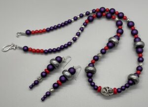 Necklace Set- Glass Pearl Purple Beads. Small Red Acrylic Beads. Small Round Silver Metal Beads. Antique Silver Electroplated Glass Beads. Silver Flower Metal Beads. Red Glass Disc Beads. Pewter Cut-Out Oval Bead Centerpiece. Approx. length: 24 inches. Hand Shaped .925 Sterling Silver Earwire. Approx. length: 3 inches. Pronounced: AH-MAH-KAH. Origin: Africa. Meaning: Beautiful-Good