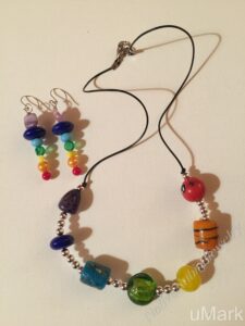 Chakra. Necklace Set- Gems, Stones, and Glass Beads. Silver Metal Bead Accents. Leather Strung. Approx. length: 22 inches. Chakra Earrings to Match. Approx. length: 2 3/4 inches. .925 Sterling Silver Earwire. Purple: Crown Chakra (Top of the Head) the Temple connects you to the Spirit Realm. -consciousness, bliss, oneness, spirituality, universal love. Indigo: Third Eye Chakra (Between The Eyes) Regulates intuition. -visualization, inner wisdom, clarity, creativity. Blue: Throat Chakra (Bottom of Throat) Regulates Expression. -communication, creative expression, confidant. Green: Heart Chakra (Middle of Chest) Regulates Emotion. -unconditional love, peace, compassion, forgiveness. Yellow: Solar Plexus Chakra (Middle of the Abdomen) Regulates Sense of Self. -drive, confidence, control, willpower. Orange: Sacral Chakra (Lower Abdomen) Regulates Creativity. -joy, pleasure, sexuality, optimism, passion, sensuality, procreation. Red: Root Chakra (Base of the Spine) Regulates Survival. -grounded, safe, firm in your place in life, glad to be alive.