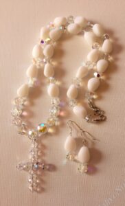 Classic Crystal and Teardrop Set- Crystal Bicone Beads. White Acrylic Teardrop Beads. Approx. length: 26 inches. Attached Cross Approx. length: 2 inches. Earrings to Match. Approx. length: 2 inches. .925 Sterling Silver Earwire.