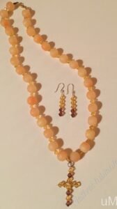 Golden Cross Necklace Set- Light Coral Frosted and Textured Acrylic Beads. Golden Light Crystal Bicone Beads. Approx. length: 22 1/2 inches. Attached Cross: Golden Light and Dark Crystal Bicone Beads. Approx. length: 2 inches. Earrings to Match: Approx. length 2 inches. 14k Gold Filled Earwire.