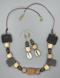 Necklace Set- Drop Mix Clay-Double Sided Line Design Beads. Faceted Natural Wood Beads. Brown and Gold Clay Beads. Natural Cowrie Shells. Brown Leather Strung. Approx. length: 21 inches. Hand Shaped 14K Gold Filled Earwire. Approx. length: 3 inches. Pronounced: EE-FEE-OH-KEH. Origin: Africa. Meaning: Wisdom