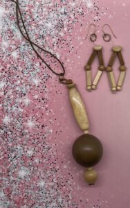 Necklace Set- Natural Puffed Wood Beads. Porcelain Tube Bead. Natural Wood Rondelle Accent Beads. Large Polished Wood Bead. Cream Colored Wood Bead. Leather Strung. Approx. length: 24 inches. 3 inch Earrings to Match. Natural Puffed Wood Beads. Four Sided Wood Beads. Tan Wood Beads. Natural Wood Rondelle Beads. Clear Nylon Strung. 14K Gold Filled Earwire. Pronounced: sa-MUN-dah Origin: African. Meaning: Renowned Warrior